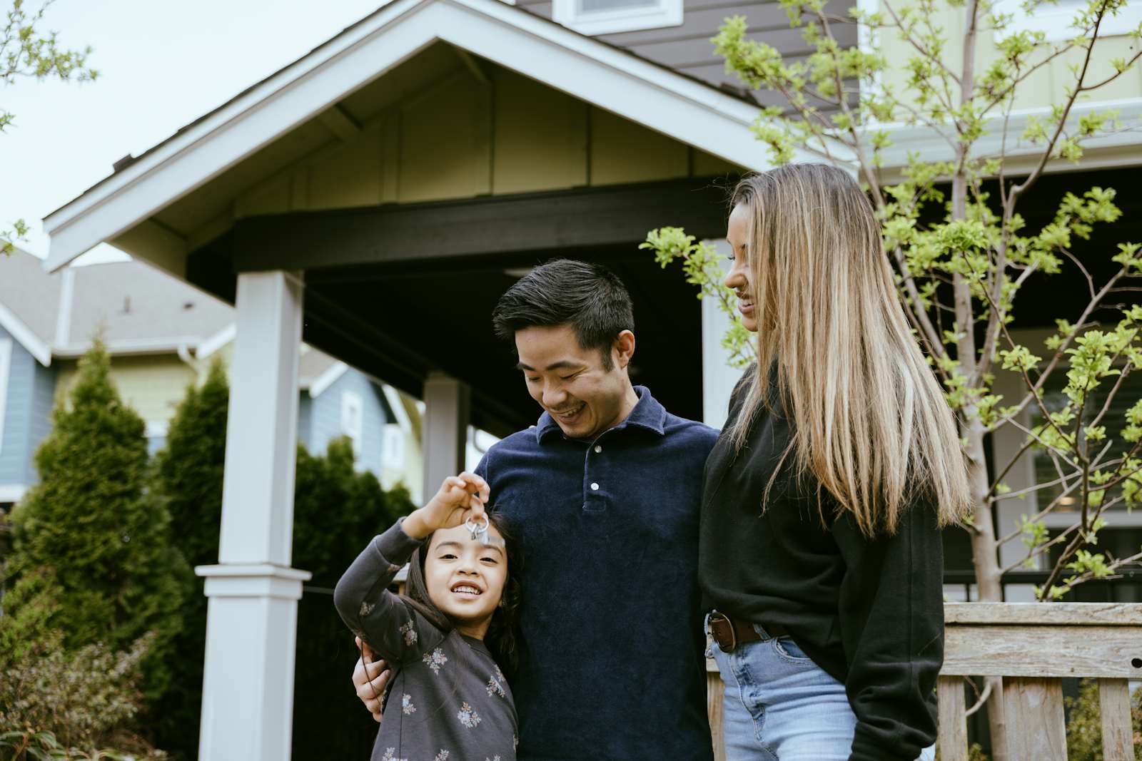 Family of three in front of new house with keys
