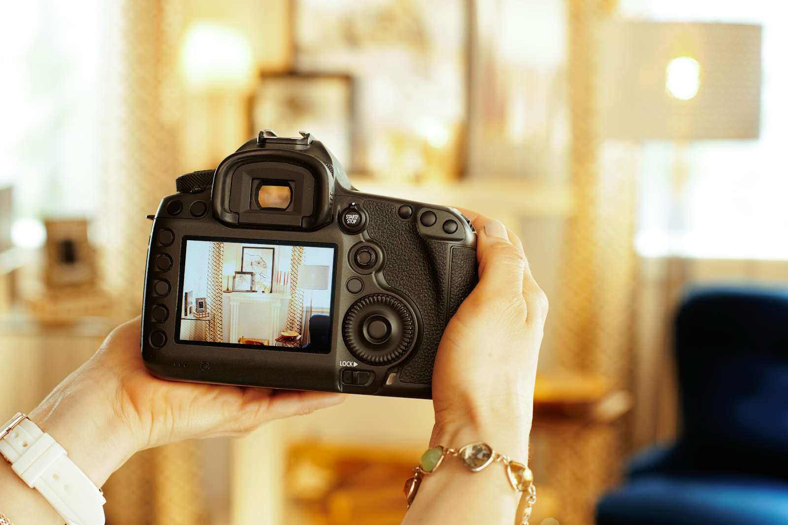 Closeup on modern DSLR camera in hand of modern female interior photographer at home