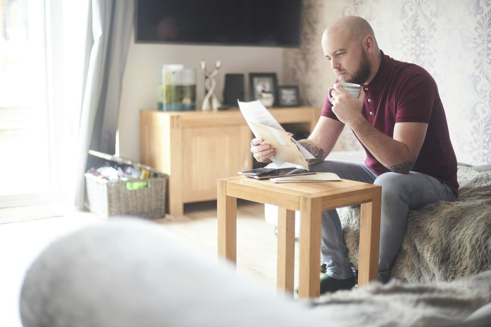 Home owner reading paperwork sat on the sofa in his living room